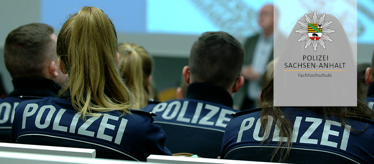 Polizeistudierende im Hörsaal von hinten zu sehen. Rechts auf hellem Grund der Polizeistern des Landes Sachsen-Anhalt darüber platziert.