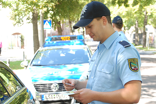 Polizeibeamter bei einer Verkehrskontrolle bei schönem Wetter in Nahaufnahme.