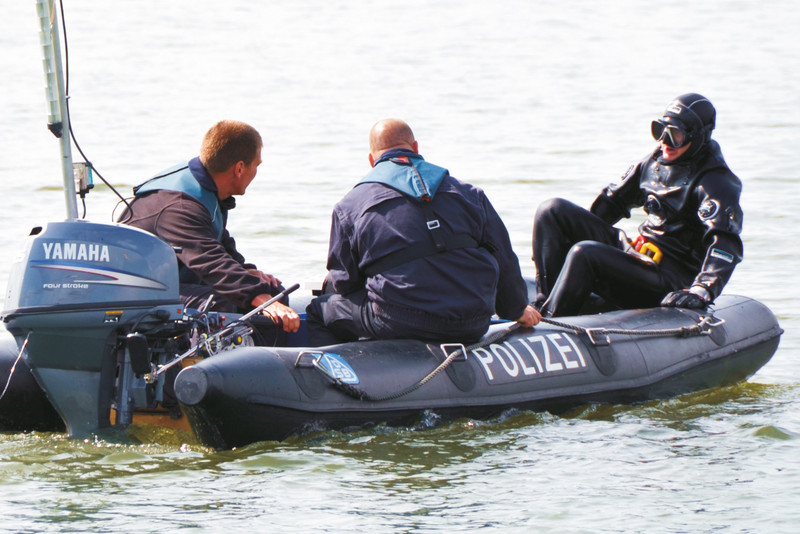 Drei Einsatzkräfte der Polizeitauchergruppe auf einem Schlauchboot der Polizei.